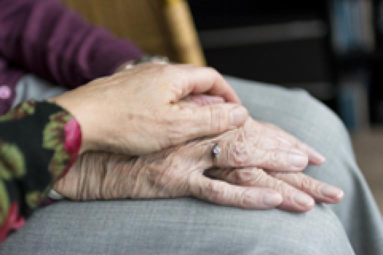 Woman's hand on elderly woman's hand with diamond ring